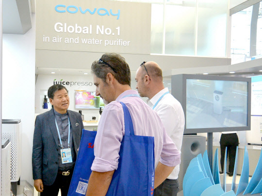 코웨이는 지난 15일부터 오는 19일까지 중국 광저우 수출입 전시회장에서 열리는 '2016 추계 캔톤 페어'에 참가한다고 17일 밝혔다. 김용성 코웨이 해외사업본부장(왼쪽)이 코웨이 부스를 찾아온 참관객들에게 와이파이 연동 공기청정기에 대해 설명하고 있다. <코웨이 제공>